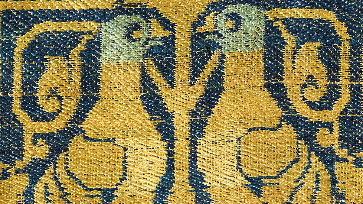 Two woven golden birds with turquoise heads face each other against a navy backdrop.